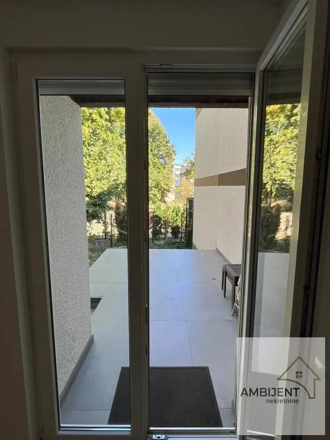 View through open balcony doors towards the terrace and yard.