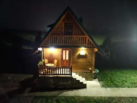 Noćni izgled drvene vikendice sa osvetljenom terasom i ulazom. - image 6