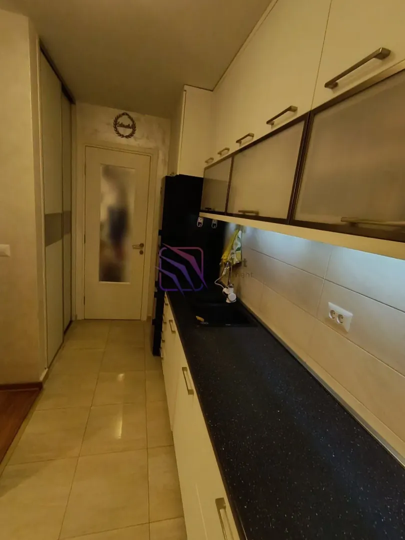 Manja kuhinja sa sudoperom, radnom pločom i gornjim elementima.