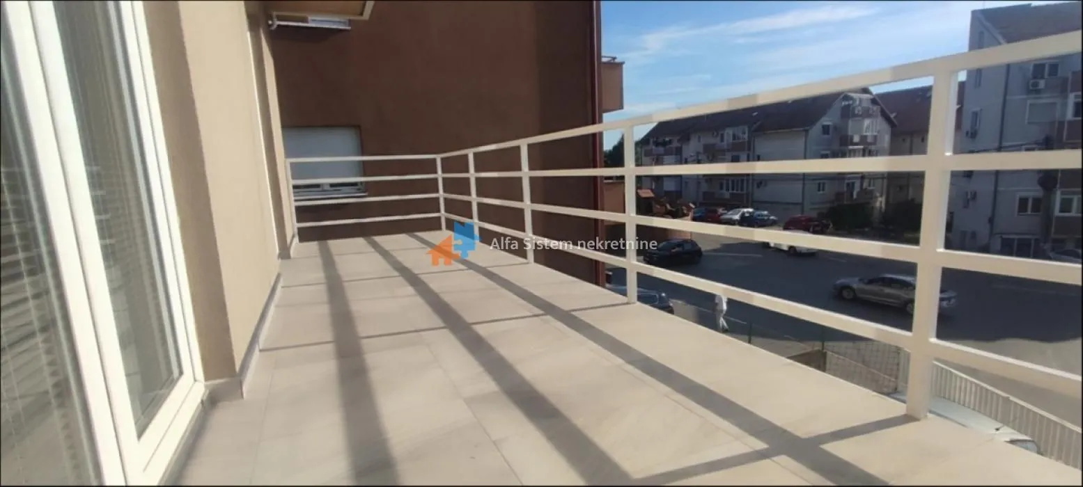 Spacious balcony with a white railing and a street view.