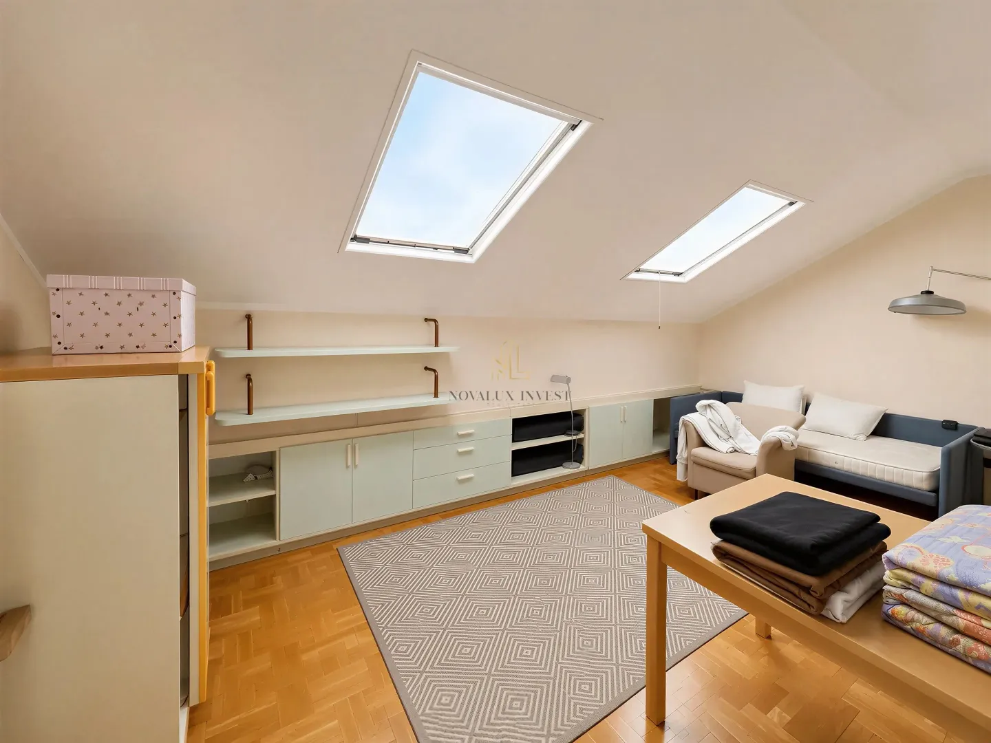 Attic room with skylights, a bed, custom-built furniture, and parquet flooring.