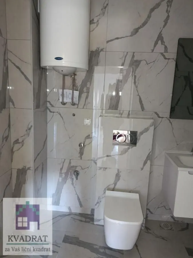Moderno kupatilo obloženo keramičkim pločicama sa sanitarijama i bojlerom.