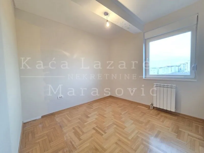 Prazna soba sa parketom i prozorom.