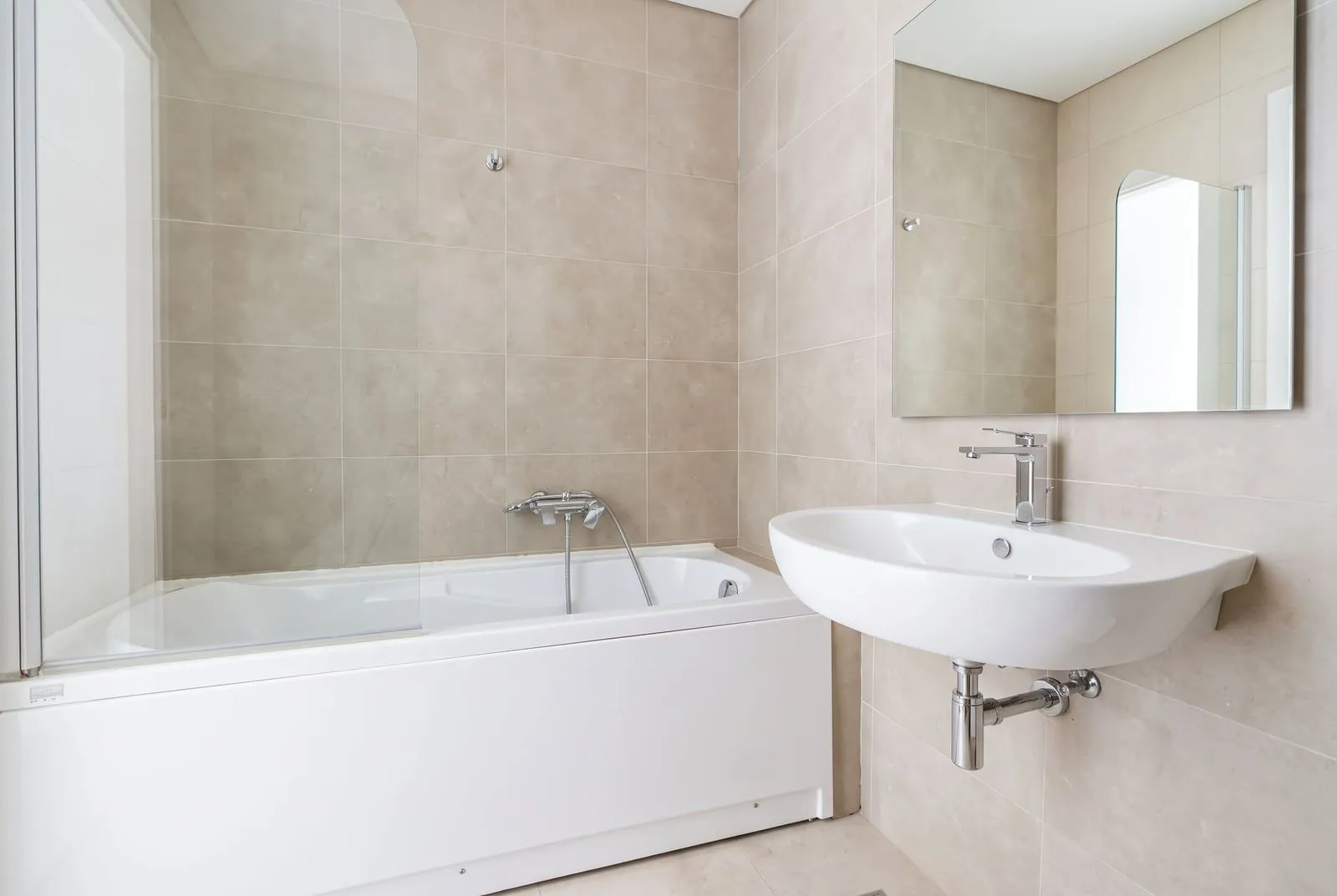 Modern bathroom with a bathtub and a sink in beige tones.