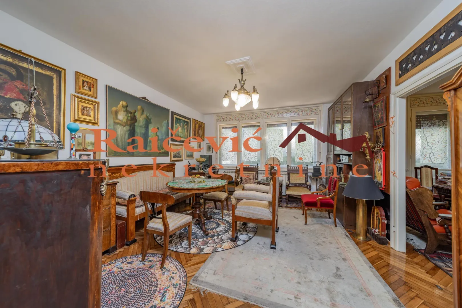 Dnevni boravak ispunjen tradicionalnim nameštajem, umetničkim slikama i detaljima.