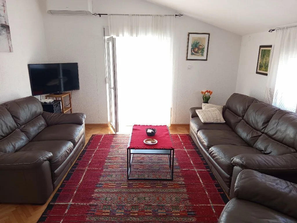 Prostrani dnevni boravak sa garniturom za sjedenje i izlazom na terasu.