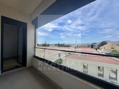 Natkriveni balkon sa staklenom ogradom i pogledom na okolnu naselja. - image 8