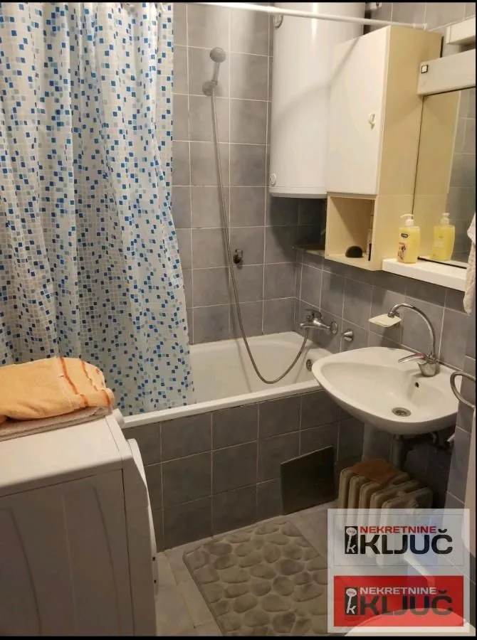 Manje kupatilo sa kadom, umivaonikom i pločicama.