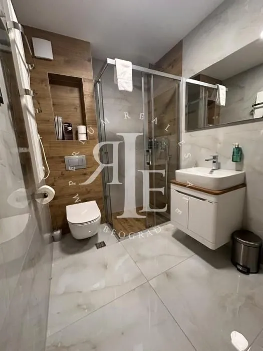 Moderno kupatilo sa tuš kabinom, umivaonikom i ugradnom wc šoljom.