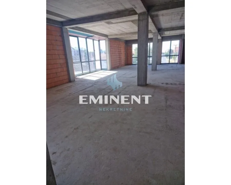 View of an empty space under construction with concrete pillars and large windows.