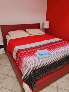 Spavaća soba sa bračnim krevetom i crvenim zidom. - image 15