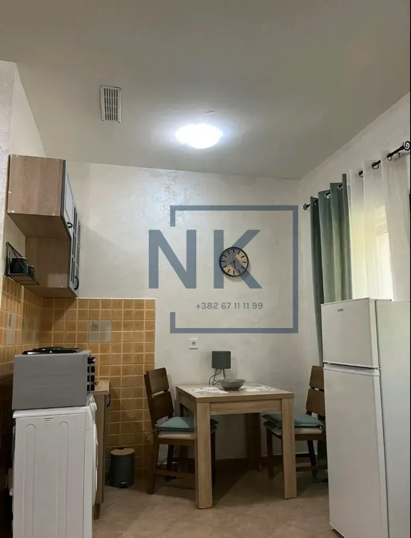 Manja kuhinja sa trpezarijskim stolom i frižiderom.