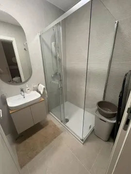 Modern bathroom equipped with a shower cabin and a vanity sink. - image 25