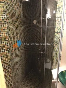 Walk-in shower enclosure tiled with mosaic tiles and featuring a glass partition. - image 17