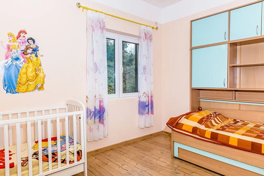 Svijetla dječija soba sa krevecom i jednim krevetom.