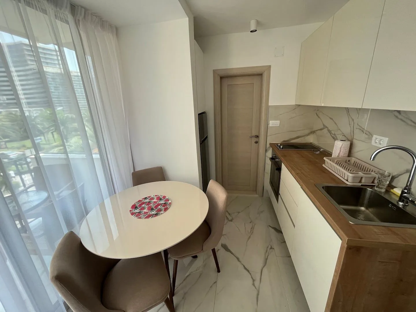 Small kitchen with a dining table and a window overlooking the terrace.