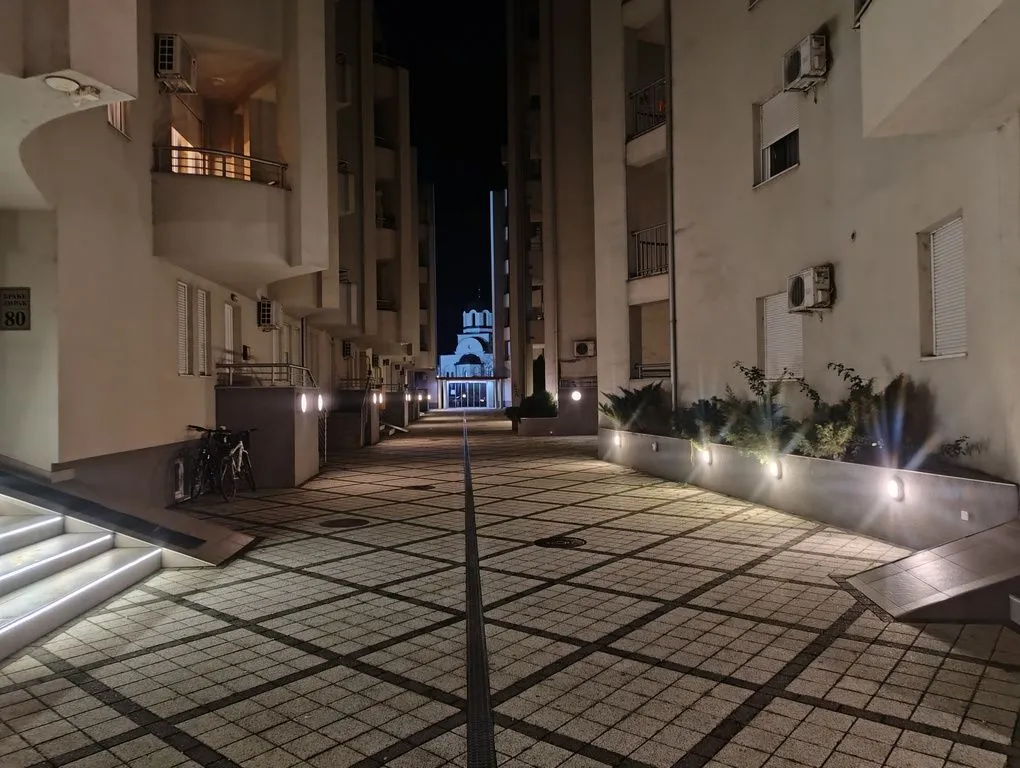 Noćni pogled na popločano dvorište između stambenih zgrada.