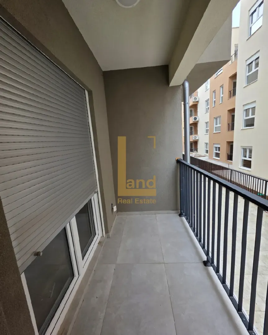 Natkriveni balkon sa pogledom na susjednu zgradu.