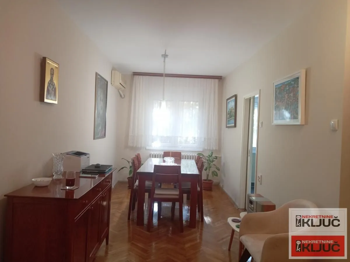 Trpezarija sa drvenim stolom, stolicama i komodom.