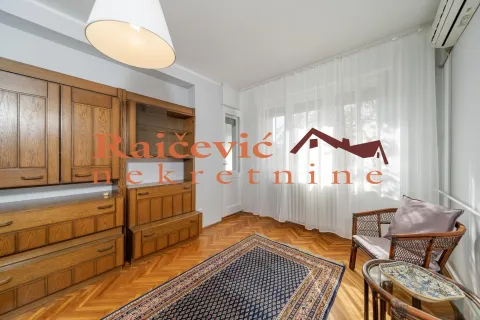 Living room with wooden furniture, parquet flooring, and a large window with white curtains. - image 12