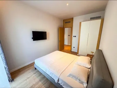 Moderna spavaća soba sa bračnim krevetom, plakarom i televizorom na zidu. - image 6