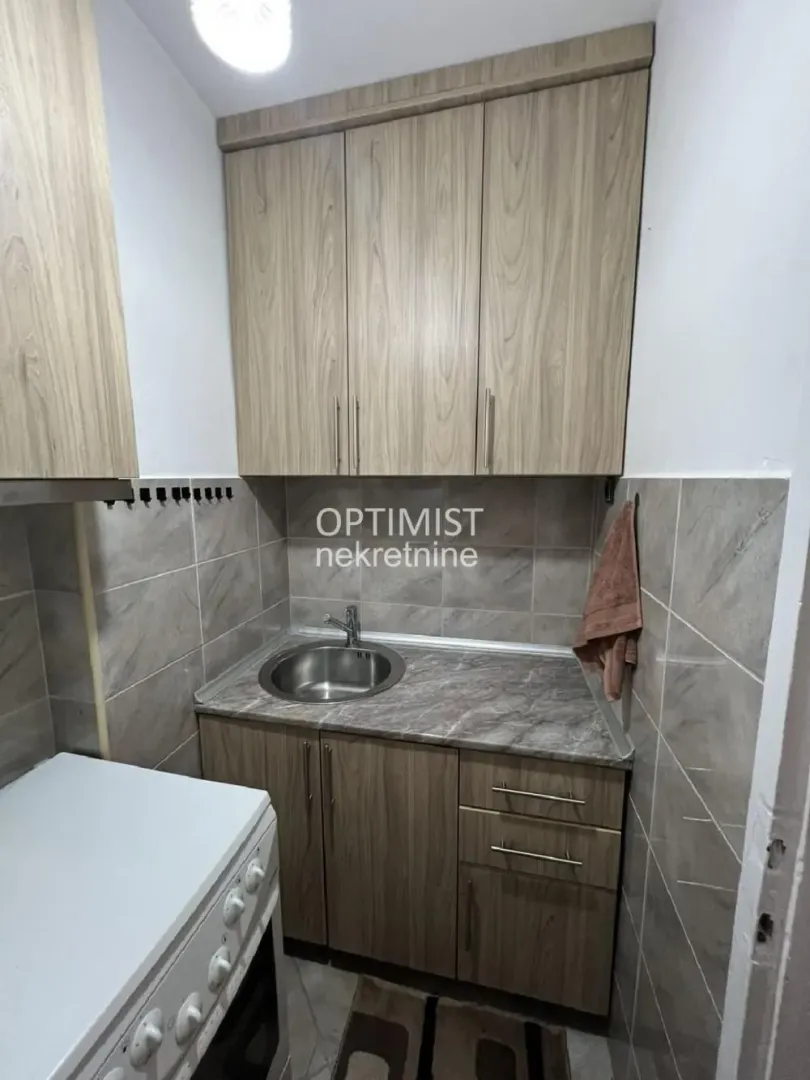 Small kitchen with wooden cabinetry, sink, and stove.