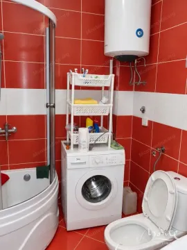Bathroom with a shower cabin, washing machine, and red tiles. - image 19