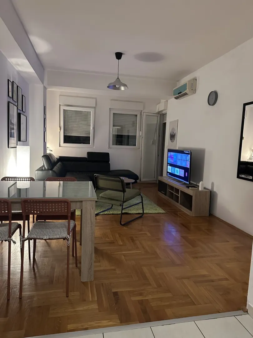 A living room featuring a dining table, corner sofa, and TV.