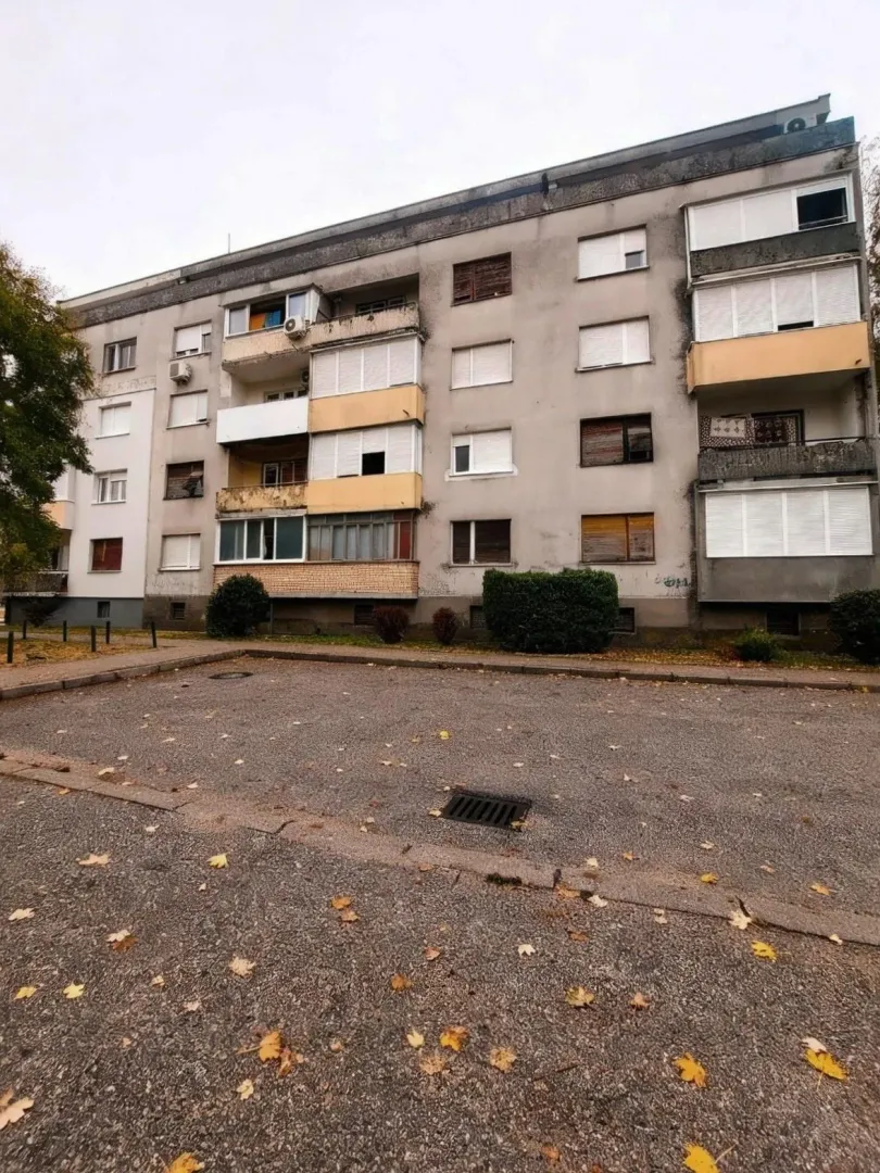 Pogled na spoljašnjost stambene zgrade i parking ispred.