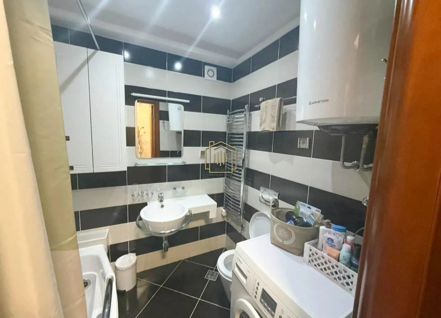Compact bathroom with a bathtub, washbasin, and washing machine.