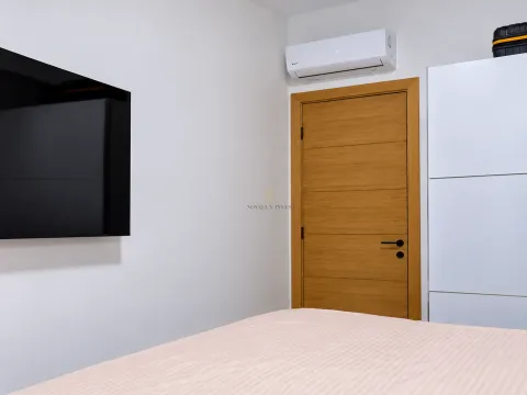 Spavaća soba sa krevetom, televizorom na zidu i klima uređajem. - image 12
