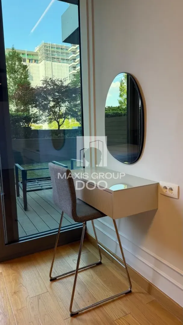 Corner with a desk and mirror next to a large window.