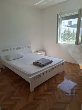 Svijetla spavaća soba sa bijelim bračnim krevetom i drvenim parketom. - image 9