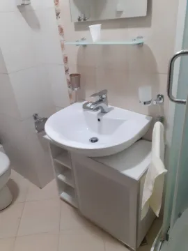 A simple bathroom featuring a white sink and a vanity cabinet. - image 8