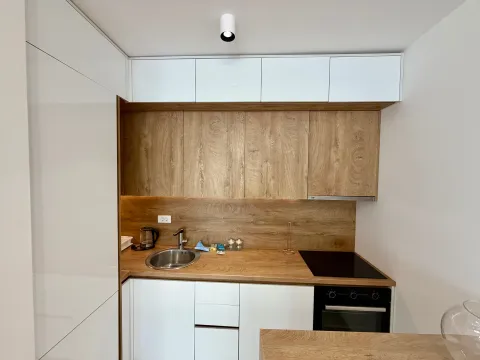 Modern kitchen with white units and a wood-grain countertop. - image 4