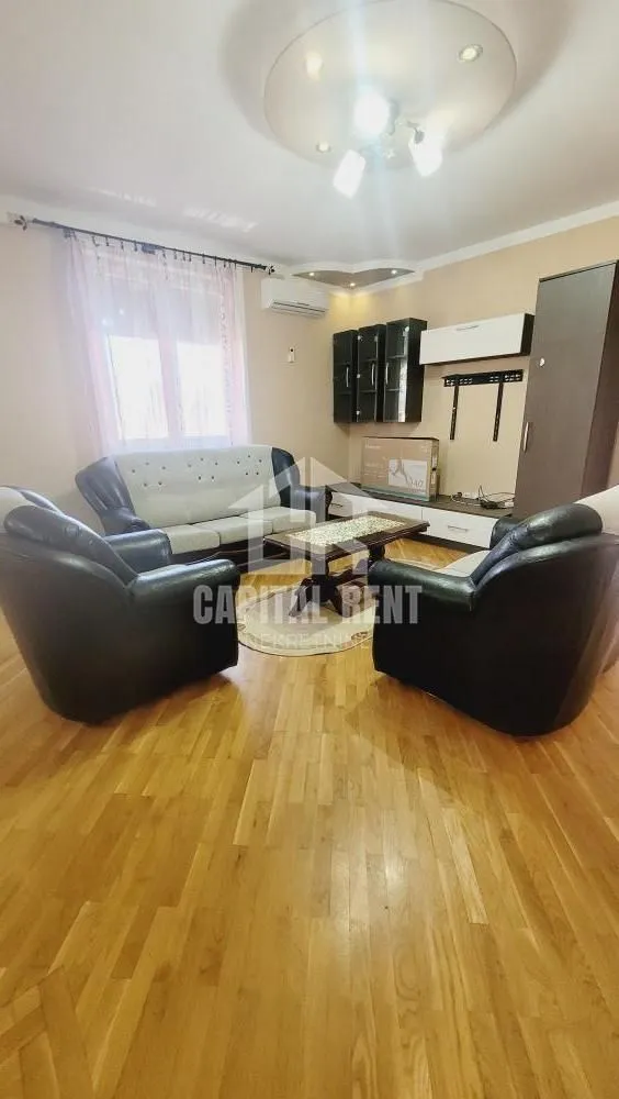 Dnevna soba sa garniturom za sedenje i TV komodom.