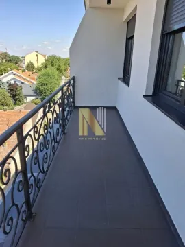 Dugačak popločani balkon sa crnom metalnom ogradom i pogledom na okolinu. - image 3