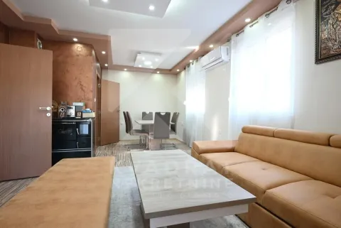 Spacious living room with a sofa, coffee table, and a dining table in the background. - image 2