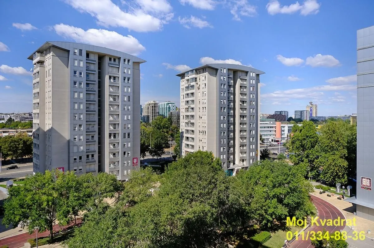 Pogled sa prozora na okolne zgrade i zelene površine.