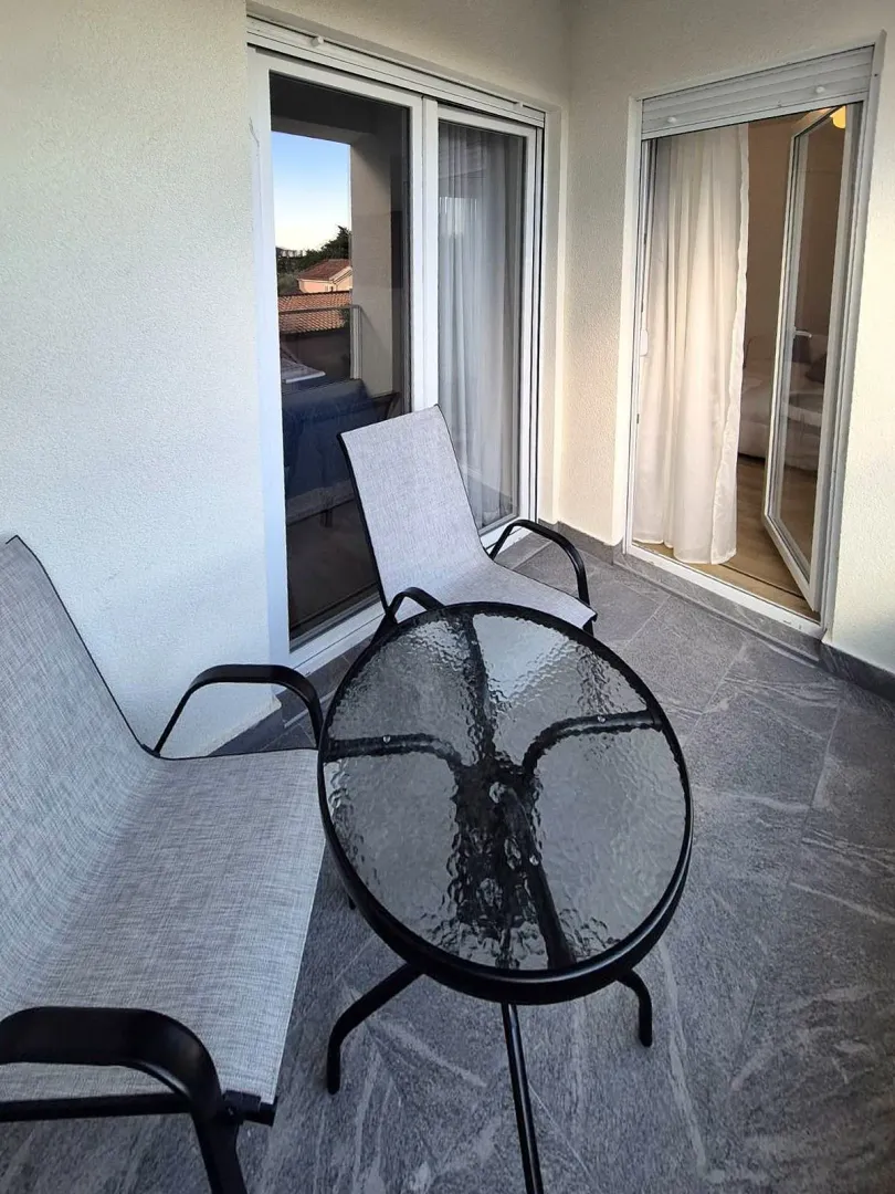 Manji namješteni balkon sa staklenim stočićem i dvije stolice.