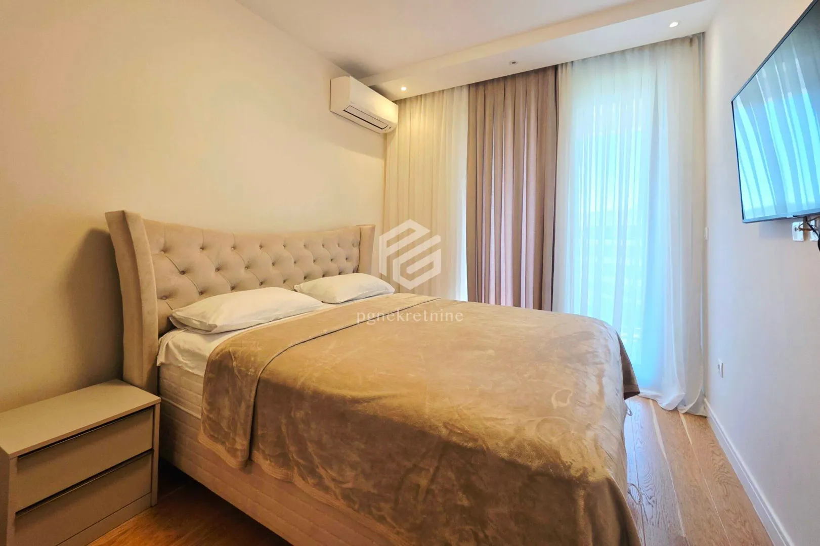 Furnished bedroom with a double bed, air conditioning, and wall-mounted TV.