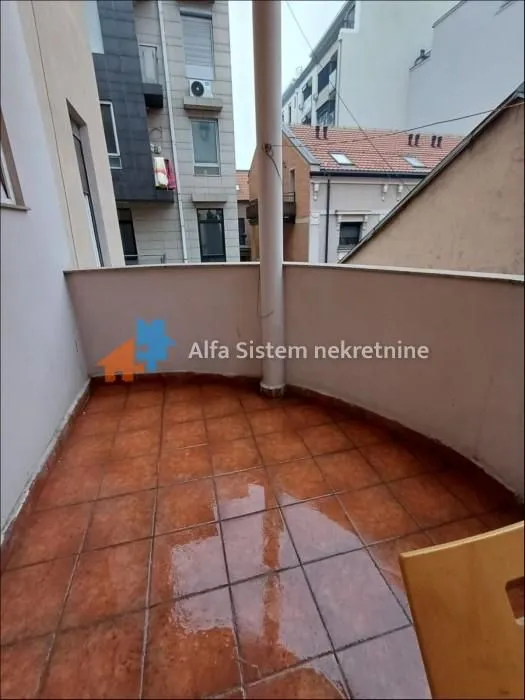 Small covered balcony with ceramic tiles and a view of surrounding buildings.