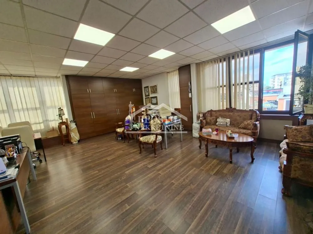 Spacious living room with wooden furniture and large windows.