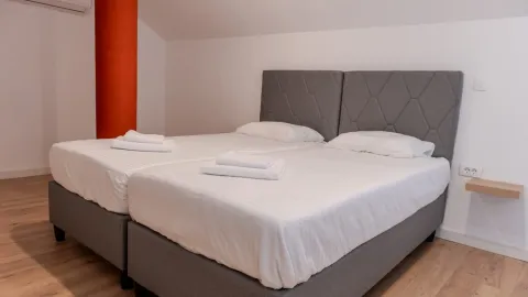 Spavaća soba sa bračnim krevetom i uredno složenim peškirima. - image 6