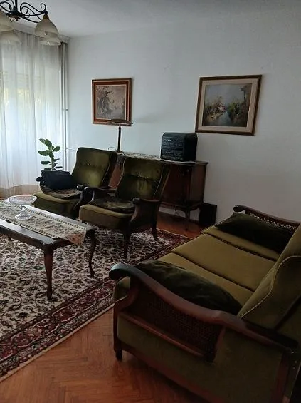 Dnevna soba sa garniturom za sedenje, stočićem i slikama na zidu.