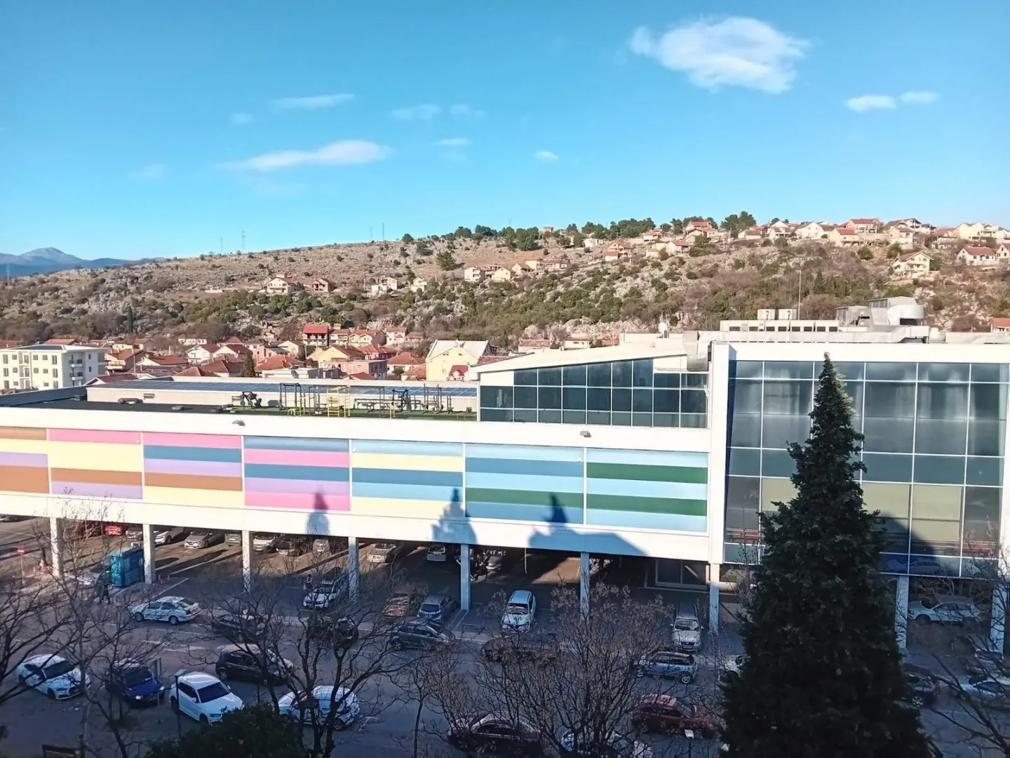 Pogled na modernu višespratnicu sa parkingom u sunčanom danu.