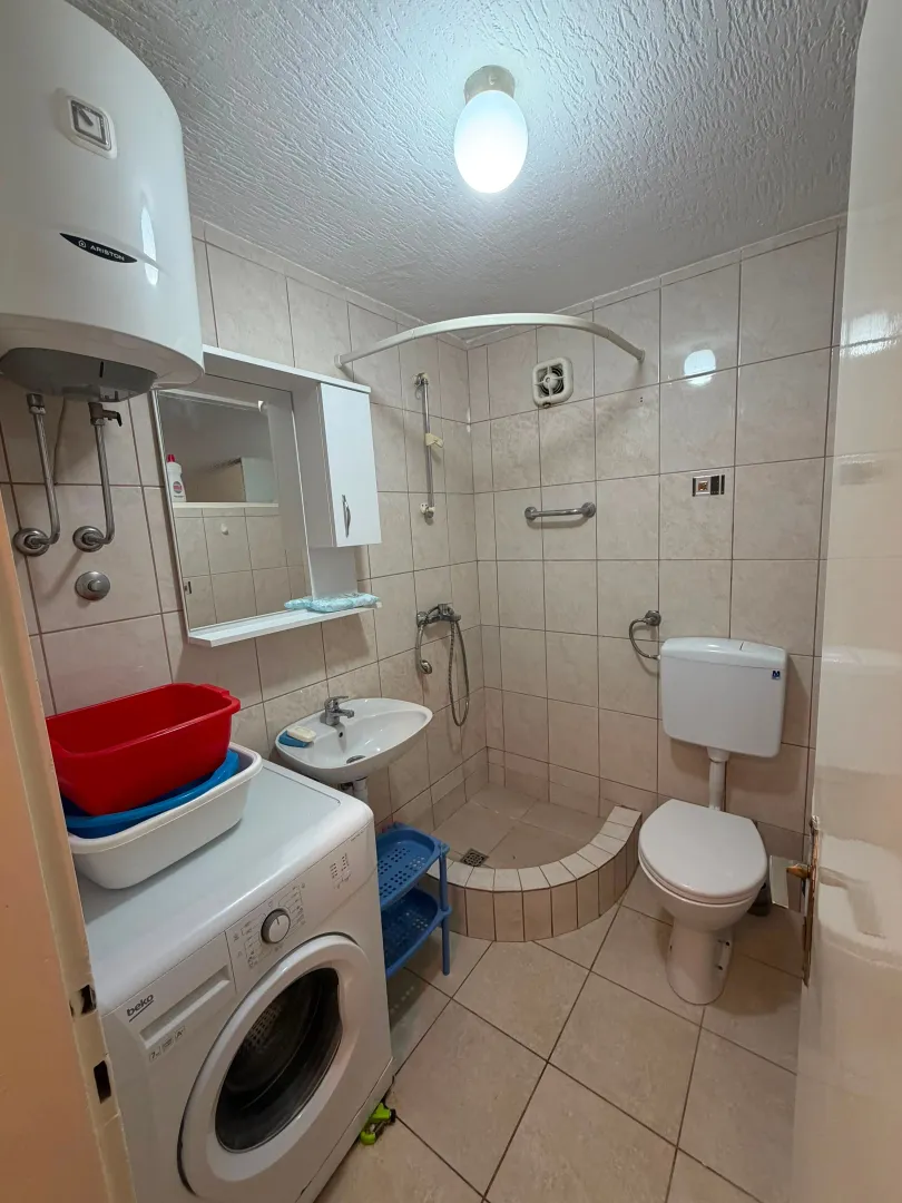 Kupatilo opremljeno tuš kabinom, umivaonikom, wc šoljom i mašinom za veš.