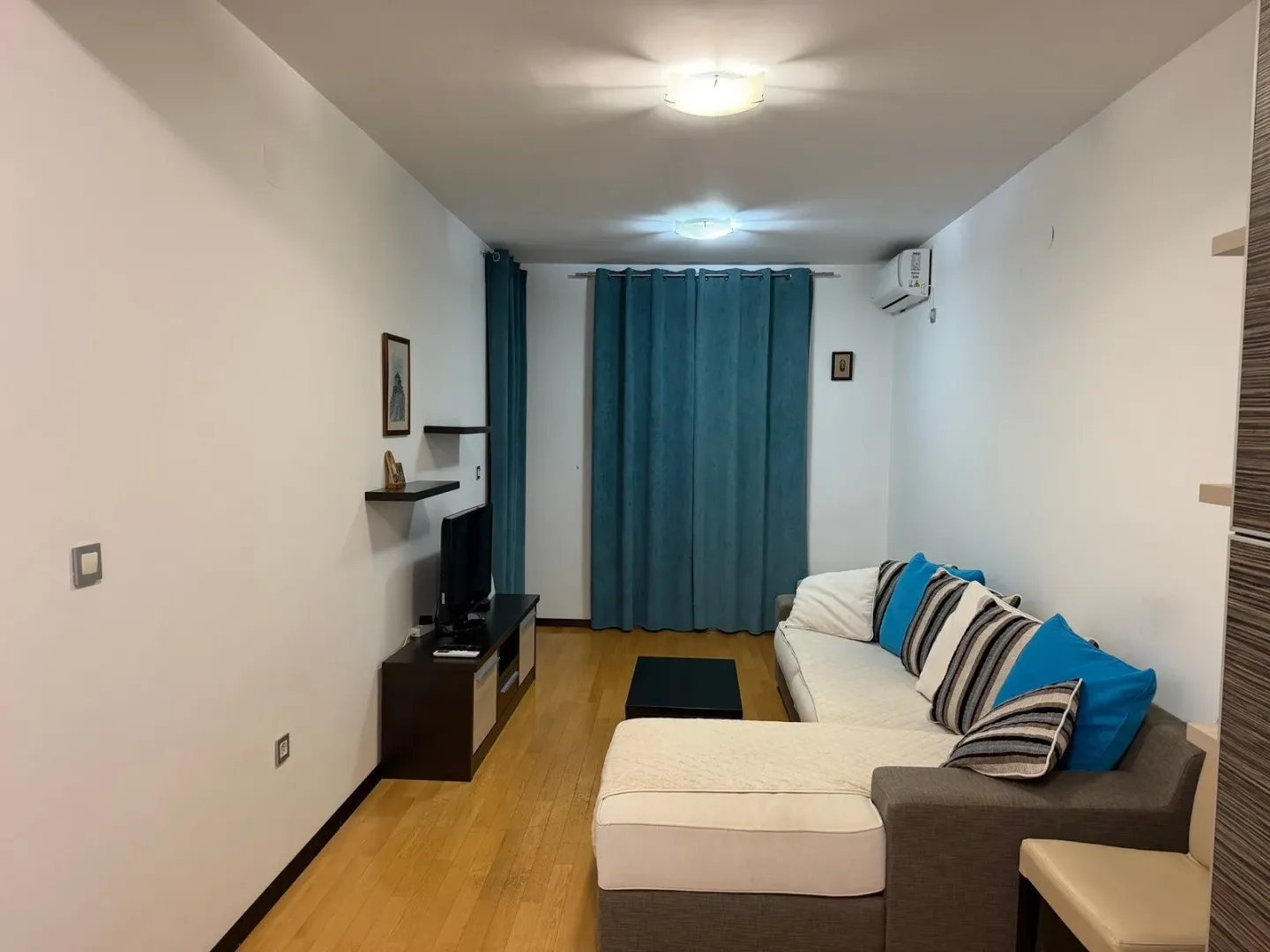 Living room with a sectional sofa, TV, and blue curtains.