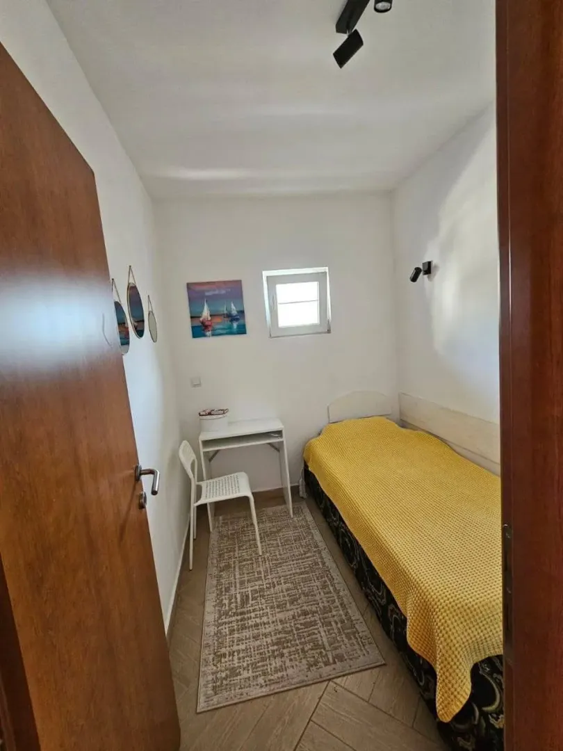 Smaller bedroom with a bed, desk, and rug.