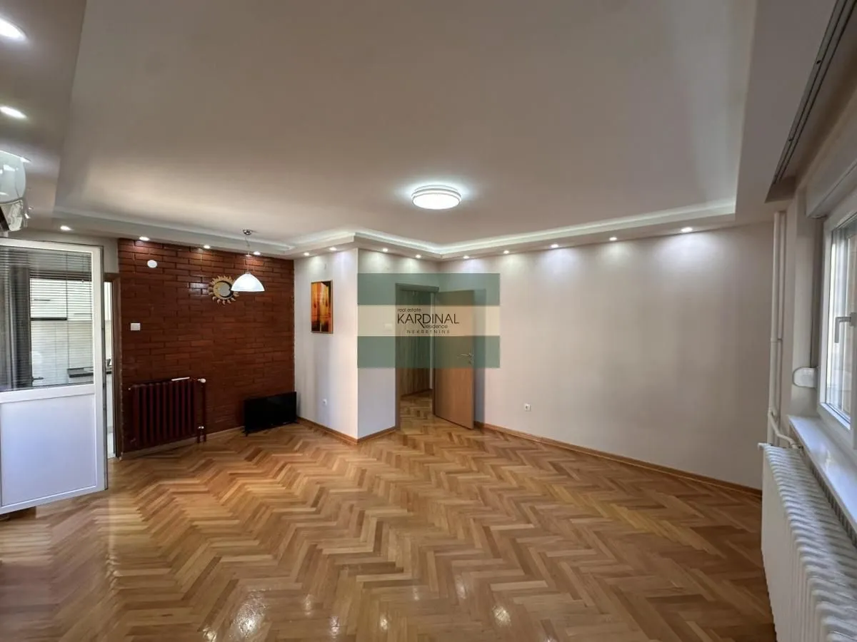 Spacious empty living room with parquet flooring and brick details.
